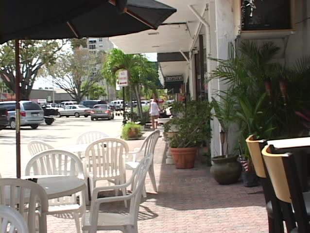 Pretty girl walking on sidewalk  and sitting down at cafe