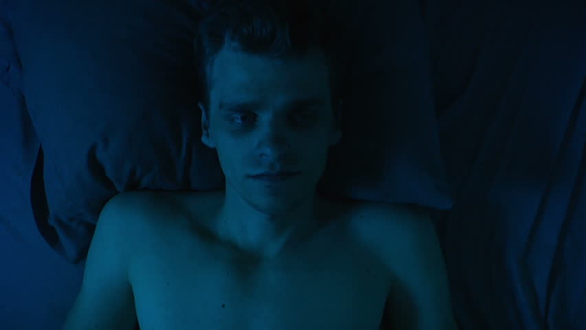 Depressed man lays on the bed.