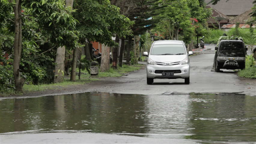 LAKE BATUR, BALI - JANUARY 21: Car driving through flooded street after downpour on Lake Batur on January 21, 2012 in Bali, Indonesia. Weather patterns have changed in recent years.