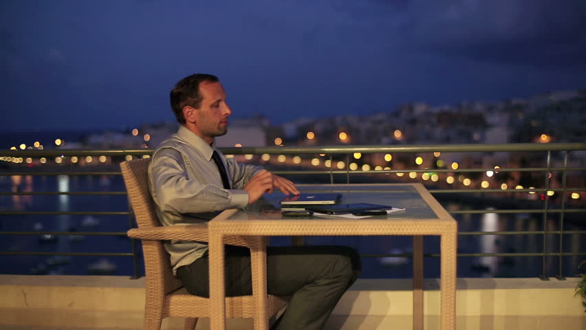 Businessman finishing work on laptop and relaxing on terrace, crane shot
