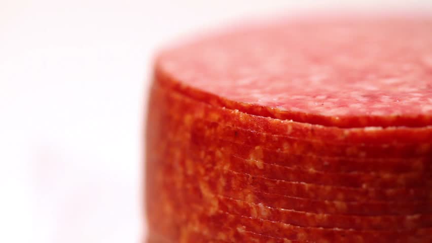 Cut and folded stack of circles revolve salami sausage on a white background in profile