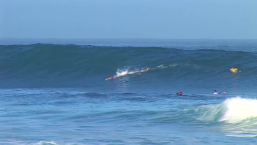Guy paddles a surfboard in to a massive tube