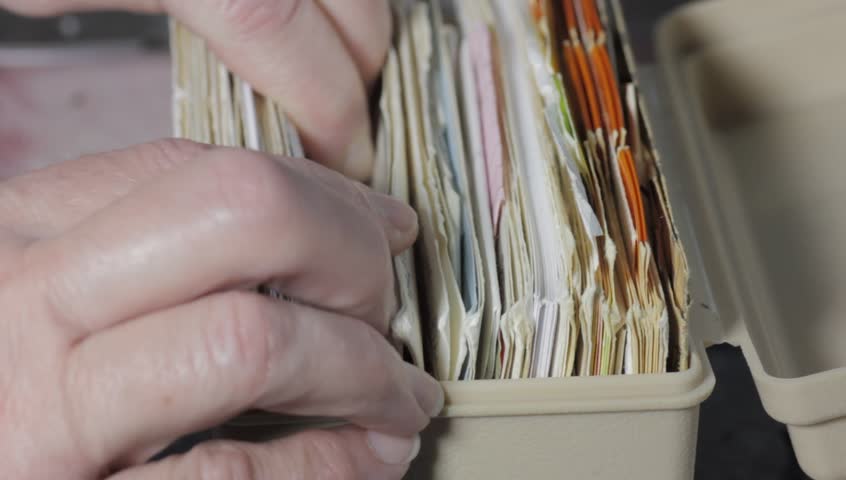 Person browsing through food recipe files close up