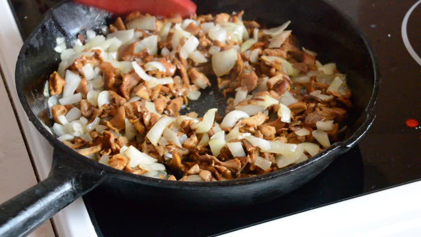 Chanterelles and onion fried in the cast-iron pan and stirred with the silicone spatula