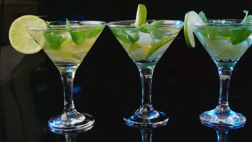 glass of cocktail with lime and mint on black background