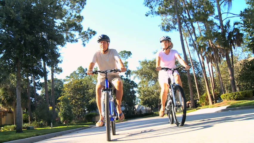 Fit & healthy senior couple enjoying retirement cycling outdoors in the sunshine