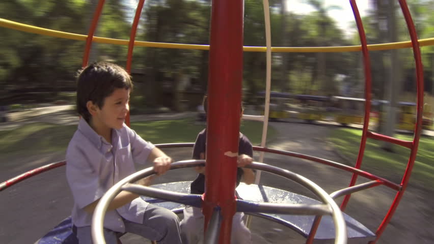 Hispanic Kid Brothers Play on Spinning Sphere at Public Playground. Inside View