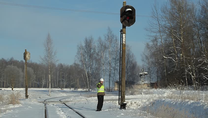 Railroad worker with cell phone near signal beacons pole