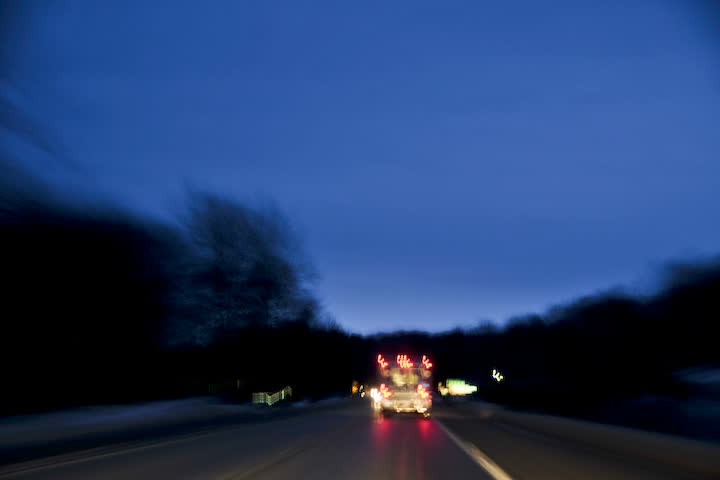 time-lapsed drive behind an on duty ambulance as it makes it's way along a rural road to the hospital. Lights are on, but not flashing. 