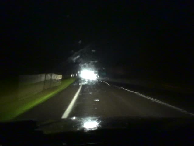 Time lapse footage of driving at night on a dark country road, passing through small villages.