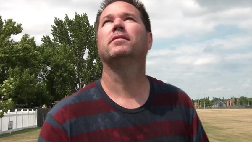 Man pours a bottle of water over his face and head in attempts to cool off on a sweltering hot summers day.