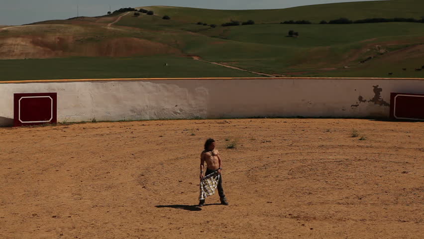 Man training as bullfighter in empty arena in a sunny day