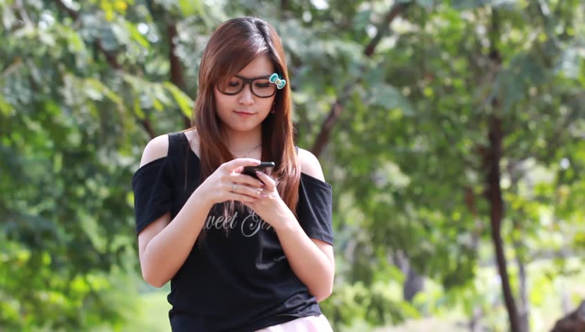 Young woman speaks by phone and smile outdoors 