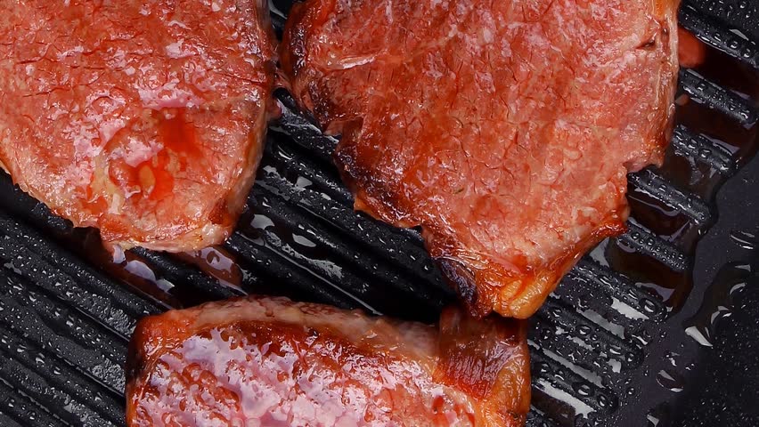 roast bloody beef fillet steaks on black teflon grill plate hidef slow motion intro
