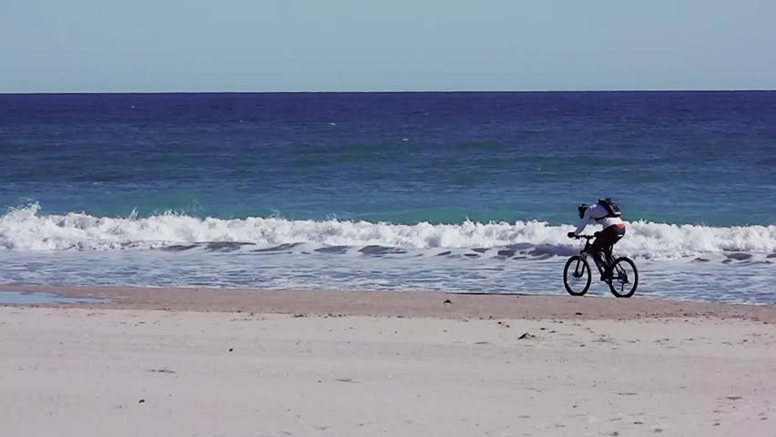 Men rides bike on beach