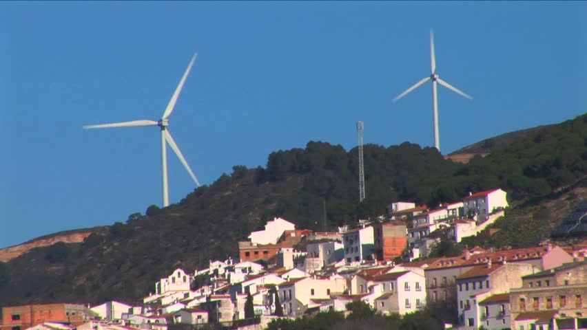 Cluster of wind turbines above a hillside village 