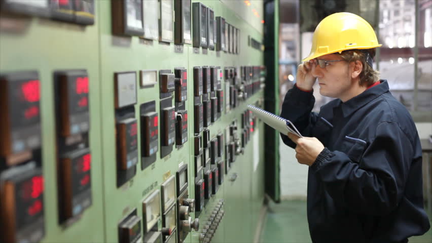 The worker writes the results of measuring devices in the control room at the factory. Shallow Doff, selective focus.