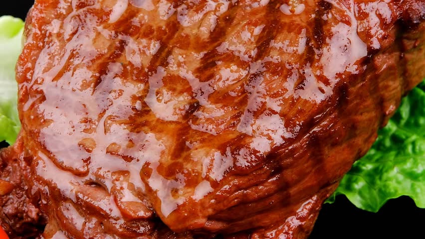 barbecued meat : beef ( lamb ) garnished with green lettuce and red chili hot pepper on black dish hidef slow motion intro