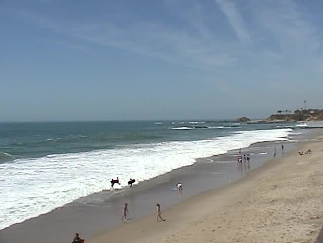 Unknown people run and play in the High Surf in Laguna Beach California in Spring Time With Sound