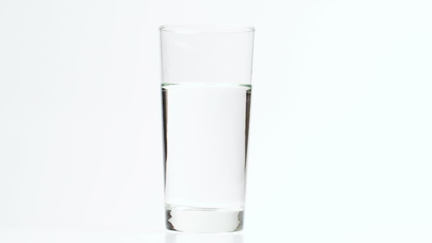 Dropping two limes in a glass of water, creating a refreshing drink.