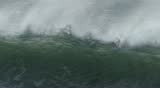 Close-up of a large, stormy ocean wave breaking in slow motion off of the coast of central California.