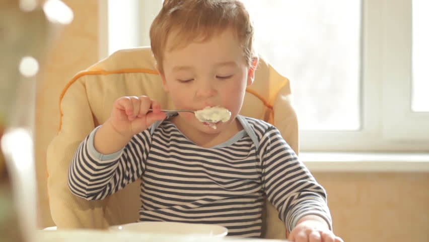 Little boy eats porridge in the morning.