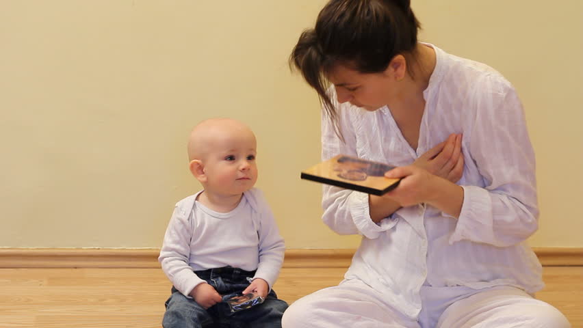 Baby imitating mother in doing cross religious sign and kissing the icon