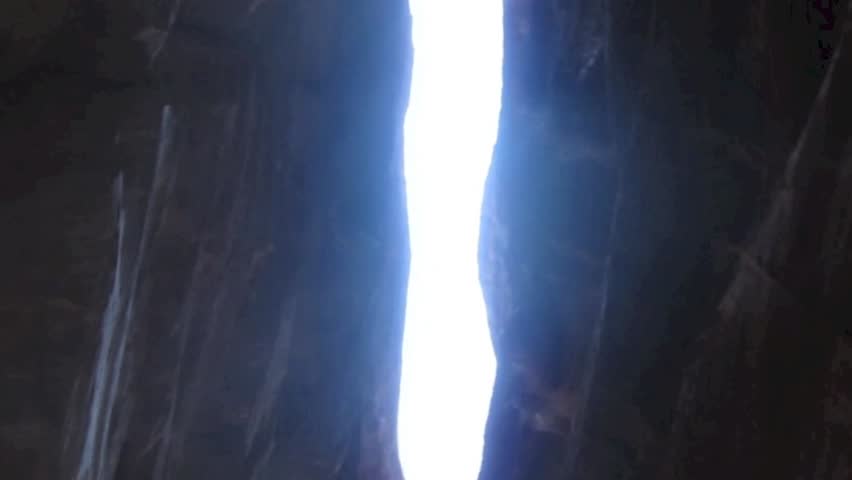 The Siq, the narrow slot-canyon that serves as the entrance passage to the hidden city of Petra, Jordan, seen here with tourists walking.This is an UNESCO World Heritage Site