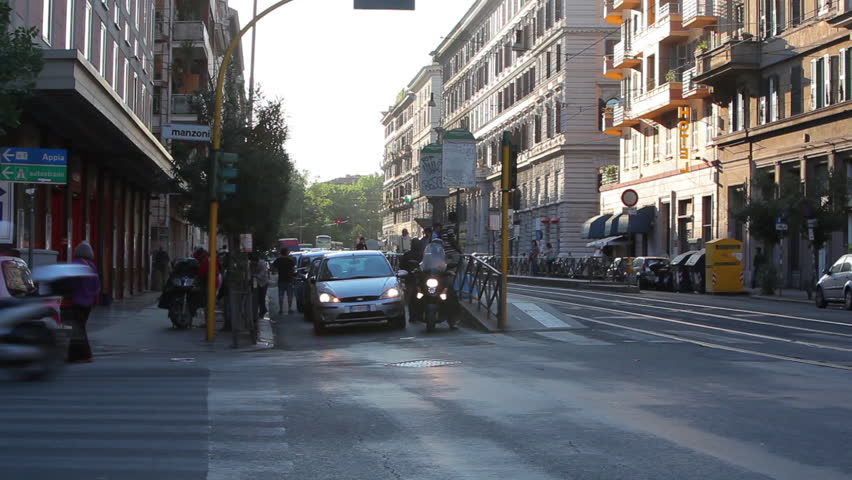 Cars and scooters drive through an intersection