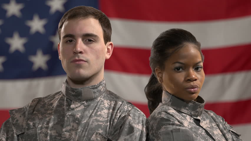 Male and female soldiers standing in front of American Flag. Shot in green screen, flag was added later. Close up 