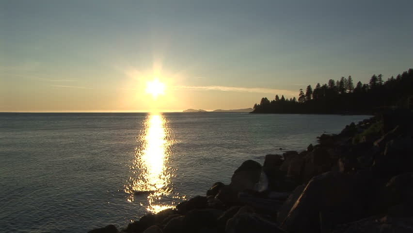 Zoom into starlight sun with golden reflection on sea at sundown
