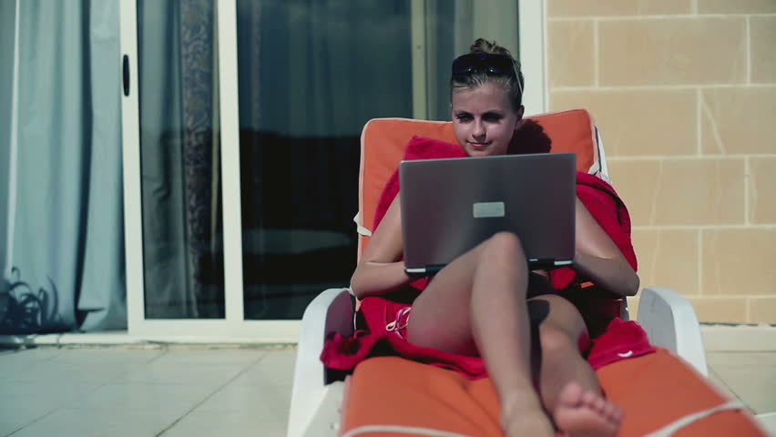 Young woman lying on sunbed finishing work on tablet computer
