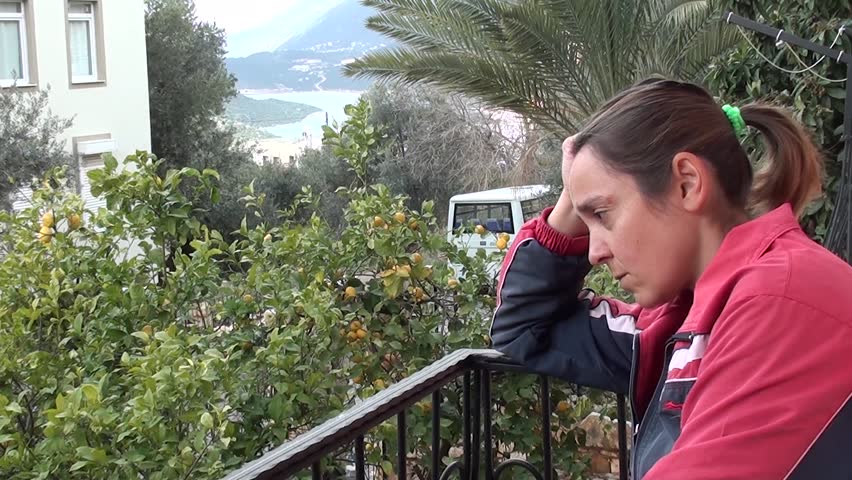 Distressed woman at balcony, stands up and leaves