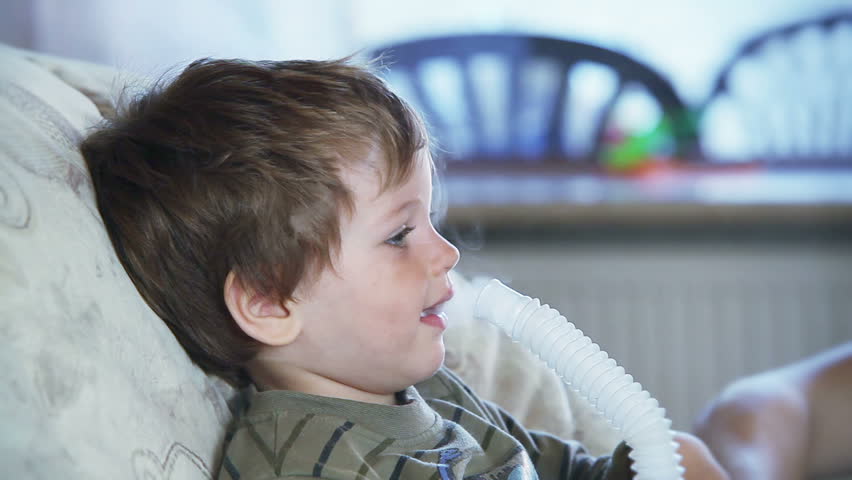 Sick little boy using nebulizer to inhale medicine
