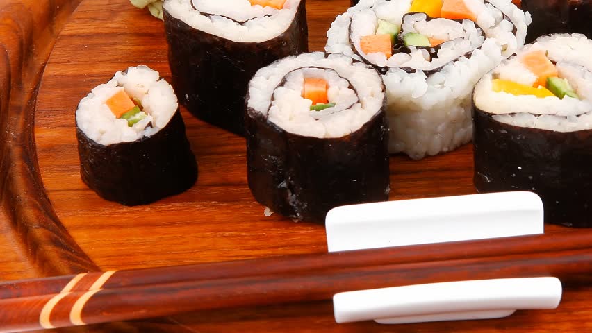 Japanese traditional Cuisine - Roll with Cucumber Cream Cheese with raw Tuna(maguro) and Salmon(sake) inside. on wooden plate with wasabi and ginger isolated over white background