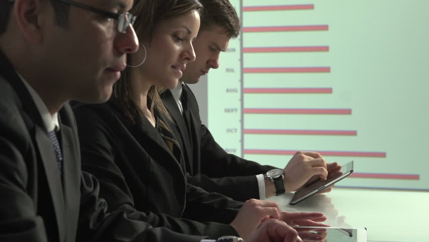 Business employees working on their tablets and laptops with graph in the background