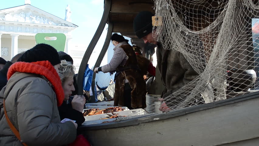 VILNIUS, LITHUANIA - MARCH 02: People buy fresh healthy ecological fish from fisherman in wooden ship imitation in outdoor street market fair near cathedral square on March 02, 2012 in Vilnius.