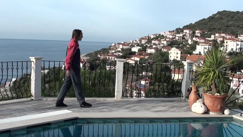 Woman touches water in swimming pool, early morning