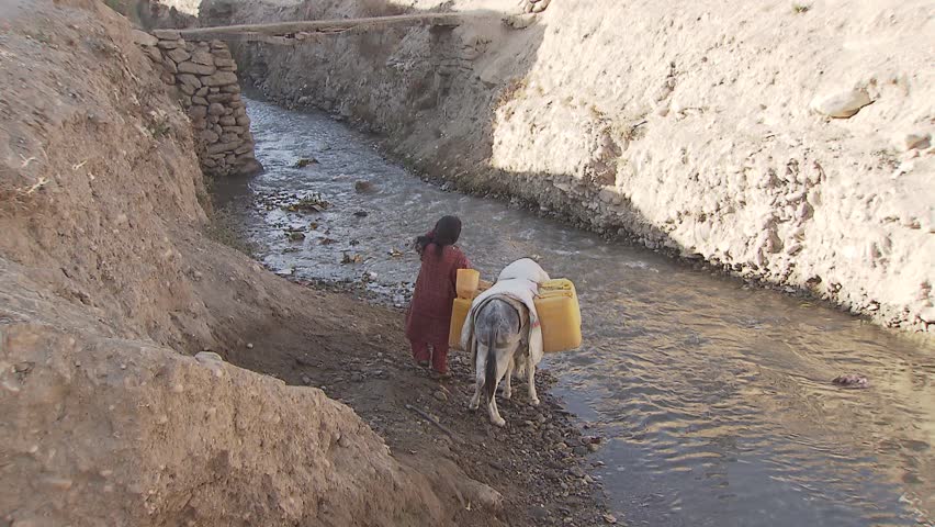 FAYZABAD, AFGHANISTAN - NOVEMBER 18: Young girl with donkey on a river getting drinking water for her family in Fayzabad, Afghanistan on November 18, 2011.