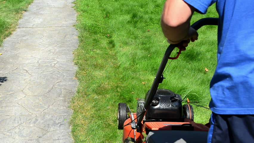 gardener man with shorts and flip-flop shoes push mower cut lawn grass near stone path.