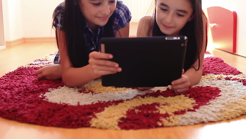 Two happy teenage girls having fun using tablet computer