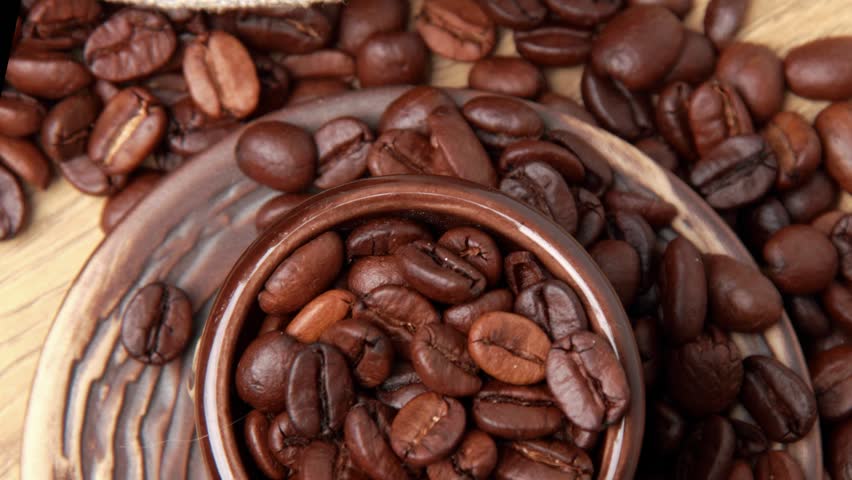 Textured background of coffee beans and brown ceramic cup
