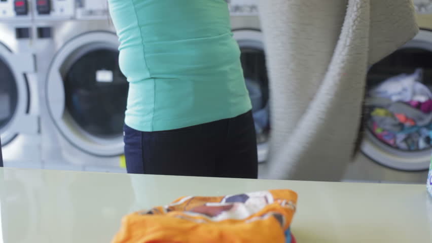 beautiful woman folding a blanket doing the laundry