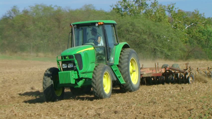 Tractor discing field with disc harrows. 