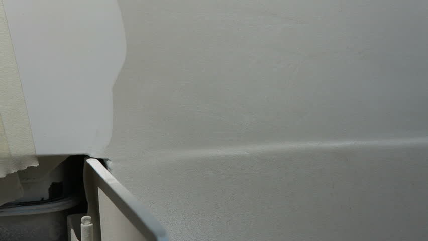 Smearing putty on damaged car surface layer by layer, close-up.