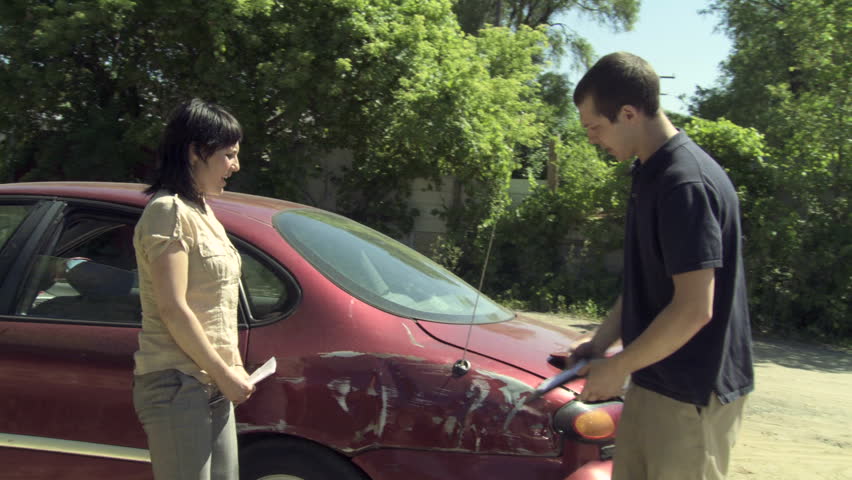 Two people get out of their cars after a collision, inspect the damage and exchange insurance details. Wide shot, develops from close up of damage. Hand held camera.