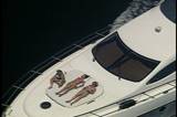 Boat riding on the Ocean with some people on the deck sun tanning 
