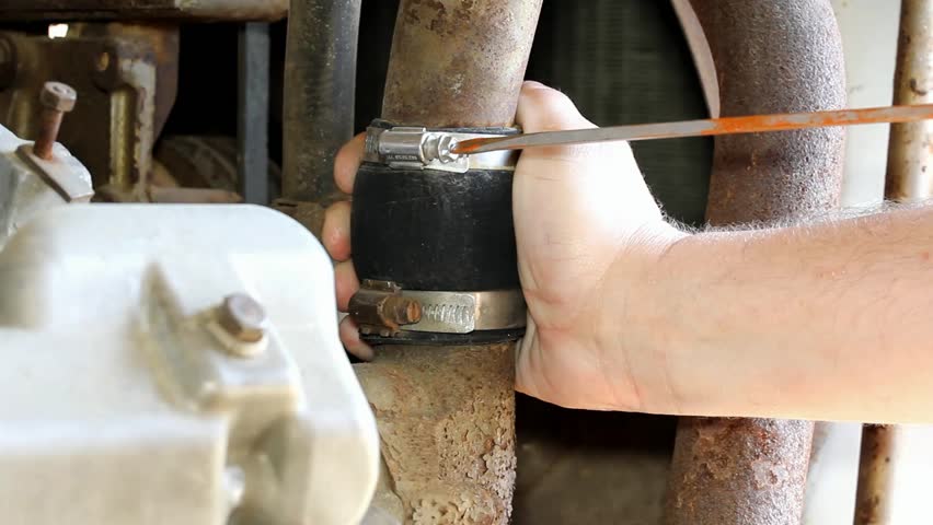 Hose Clamp On Old Diesel Engine Adjusted With A Long Flat Tip Screwdriver