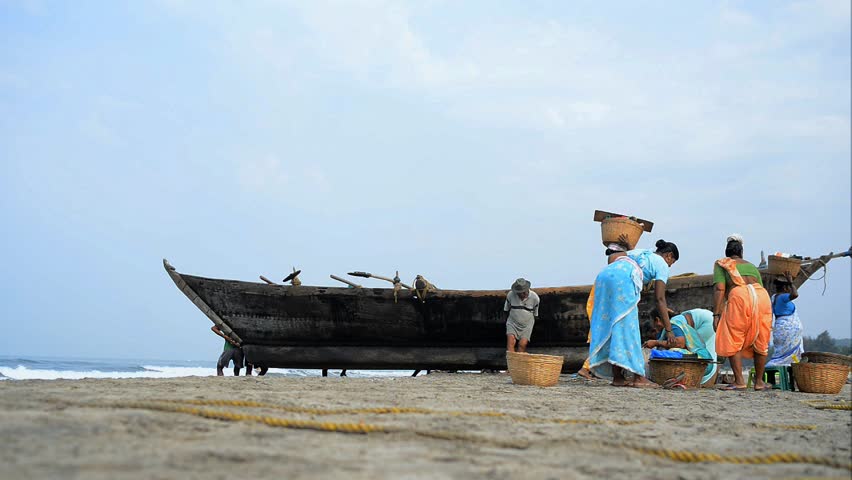 MORJIM, GOA, INDIA - MARCH 11: Fishermen drawing fisher boat onto seashore, Morjim, March 11, 2013 in Goa India. Fishing is an income source for local people.