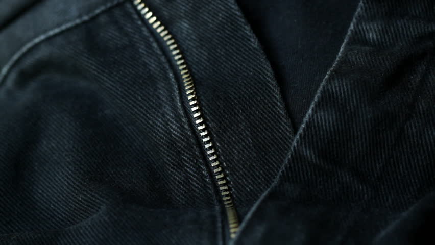 Zipping up the fly on a pair of blue denim jeans. Side view, shot with a macro lens and shallow depth of field.